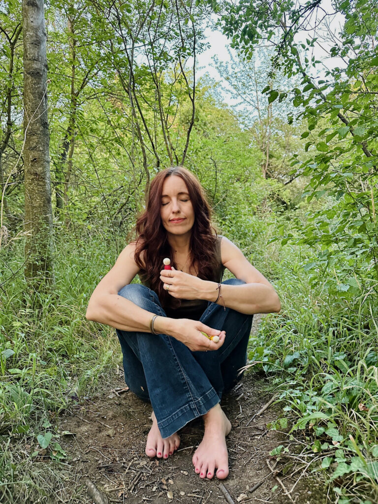 Iris Feige sitzt im Wald und fühlt was sie wahrnimmt
